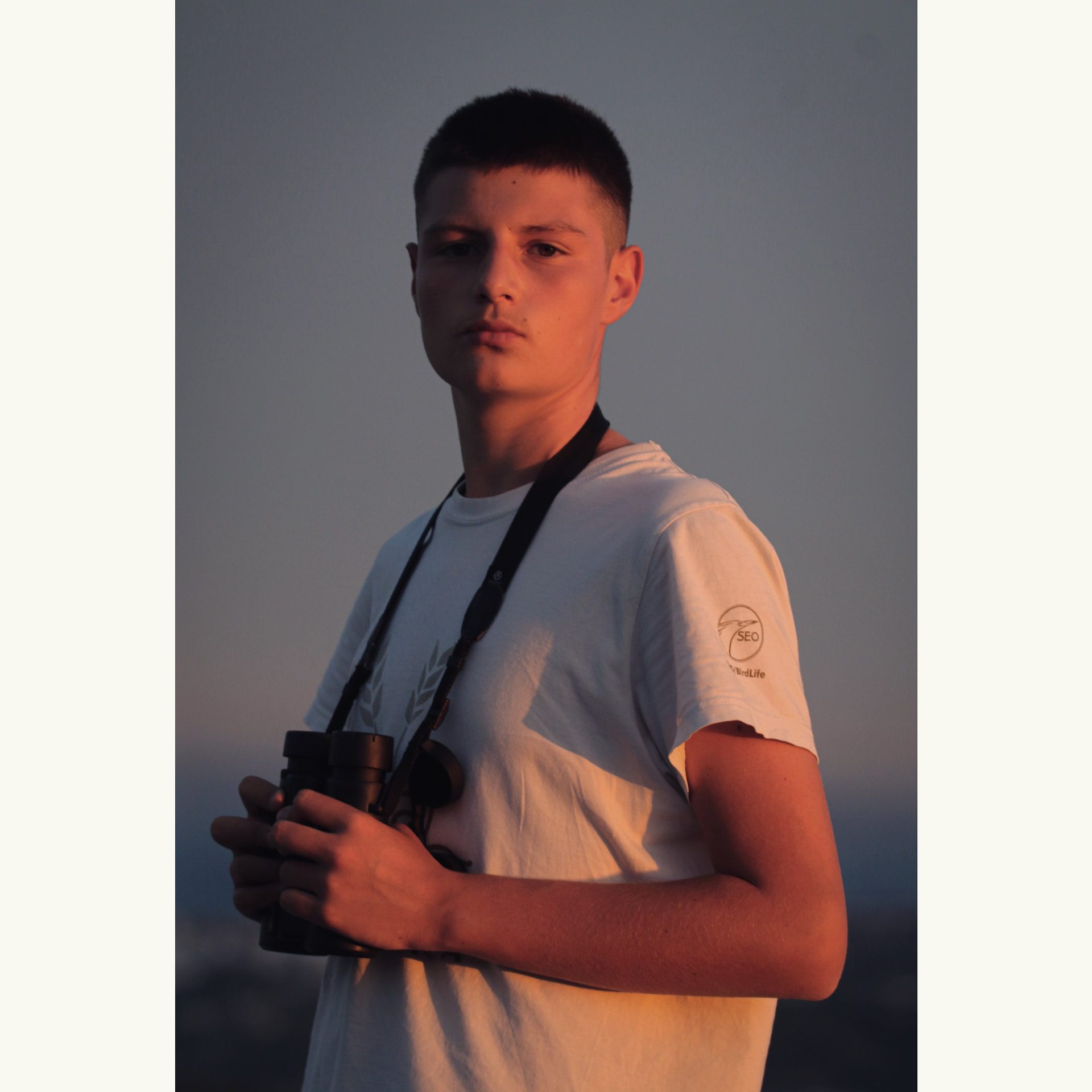 Young man with binoculars around his neck.