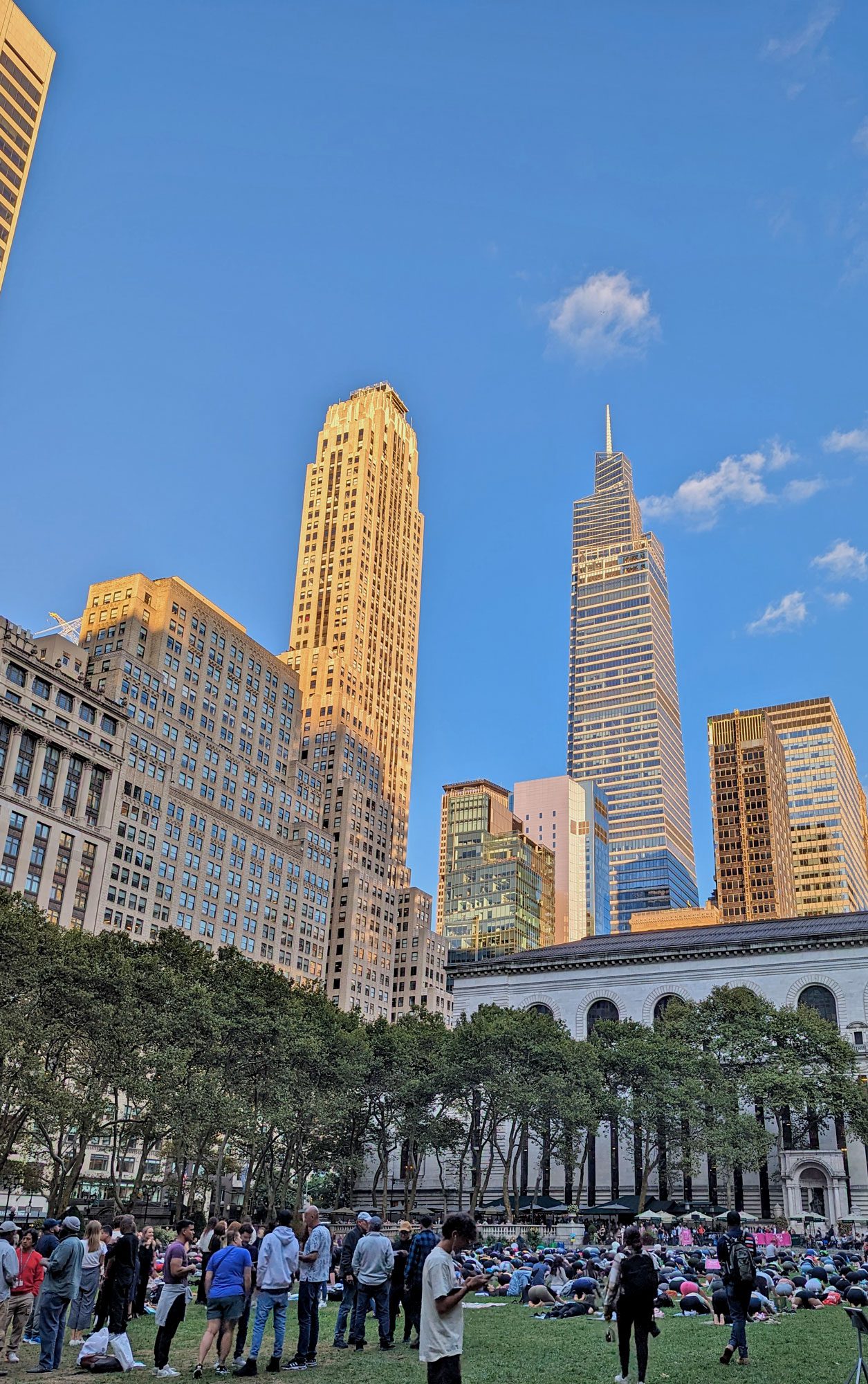 A city park with lots of people and high buildings.