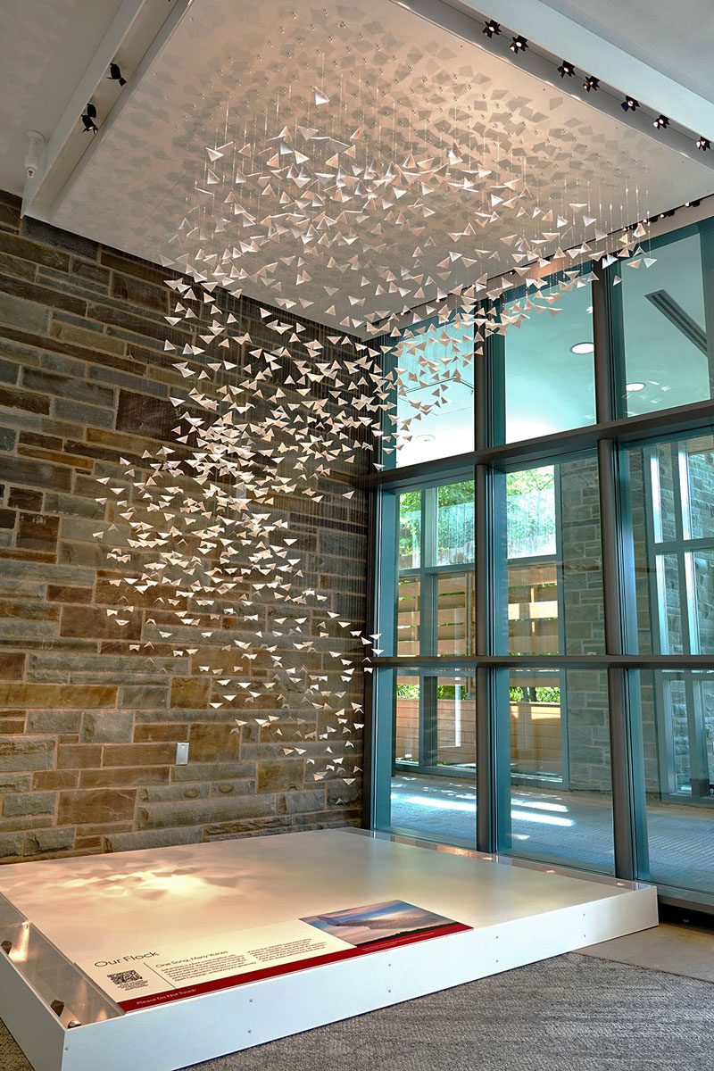 A sculpture of origami birds in the air on strings.