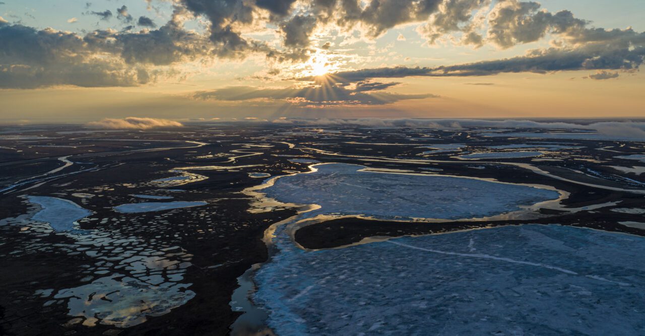 Sunset over a half frozen tundra landscape.